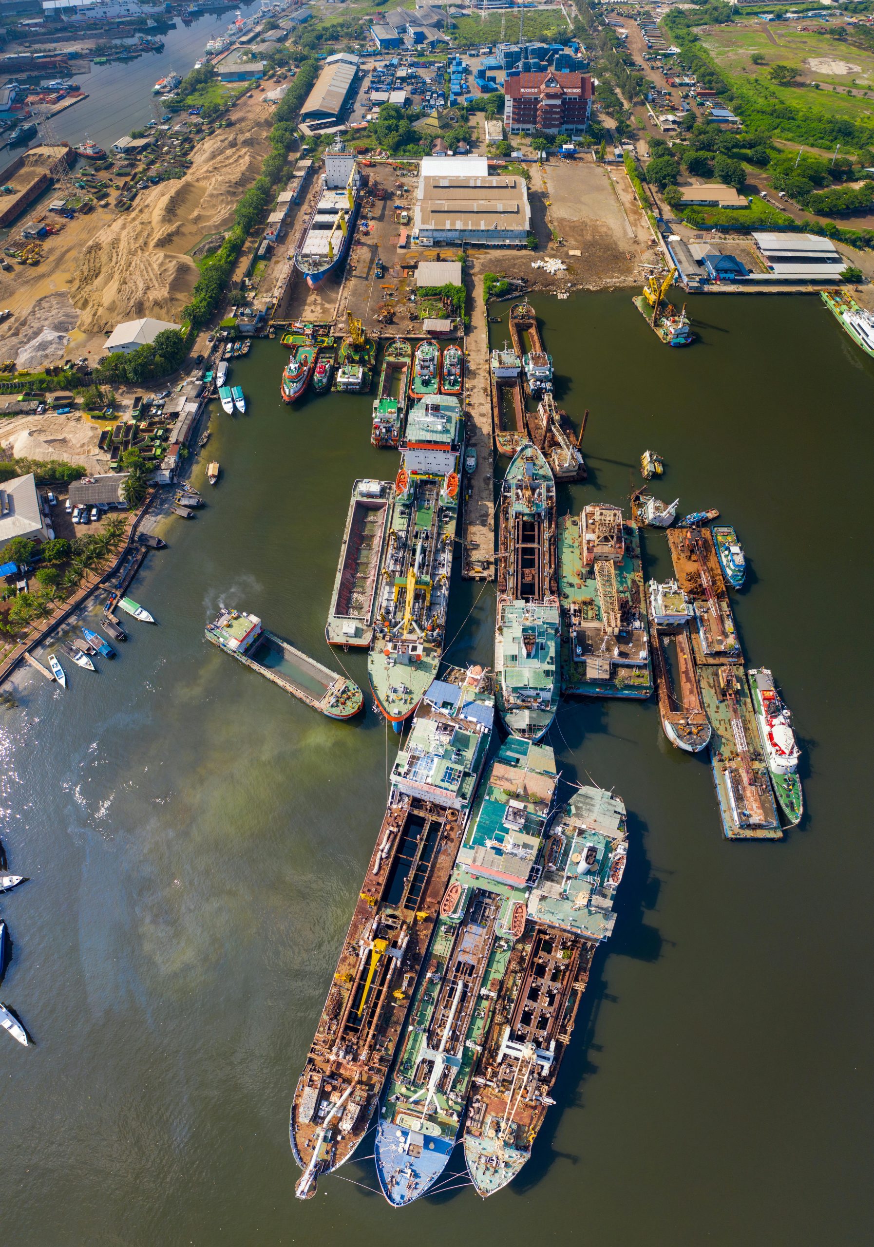 Aerial shot of a busy shipyard in Indonesia with multiple ships docked for repair.